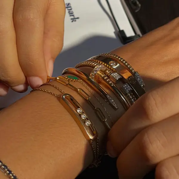Several welded bracelets and bangles on two wrists